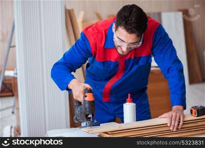The young repairman working with a power saw sawing. Young repairman working with a power saw sawing