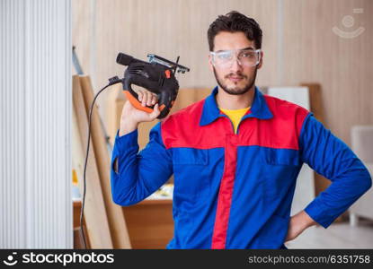 The young repairman working with a power saw sawing. Young repairman working with a power saw sawing