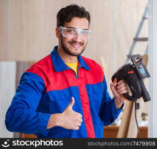 The young repairman working with a power saw sawing. Young repairman working with a power saw sawing