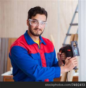 The young repairman working with a power saw sawing. Young repairman working with a power saw sawing
