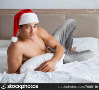 The young sexy man wearing santa hat in bed. Young sexy man wearing santa hat in bed