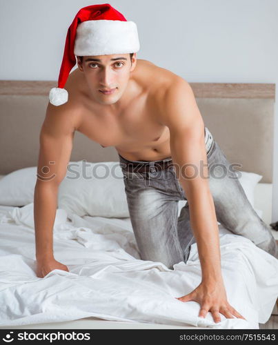 The young sexy man wearing santa hat in bed. Young sexy man wearing santa hat in bed