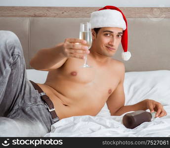 The young sexy man wearing santa hat in bed. Young sexy man wearing santa hat in bed