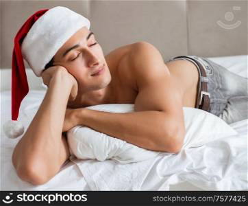The young sexy man wearing santa hat in bed. Young sexy man wearing santa hat in bed
