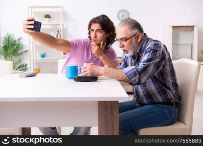 The young student and his old grandpa at home. Young student and his old grandpa at home