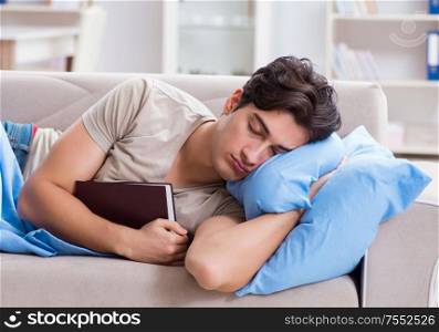 The young student man preparing for college exams in bed with book. Young student man preparing for college exams in bed with book