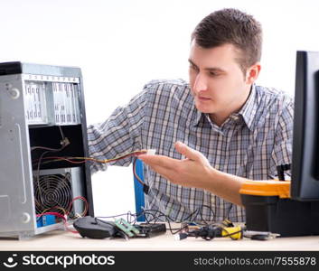 The young technician repairing computer in workshop. Young technician repairing computer in workshop