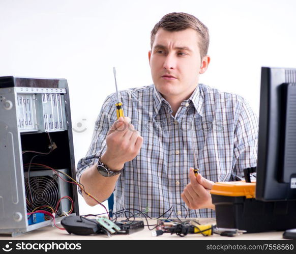 The young technician repairing computer in workshop. Young technician repairing computer in workshop