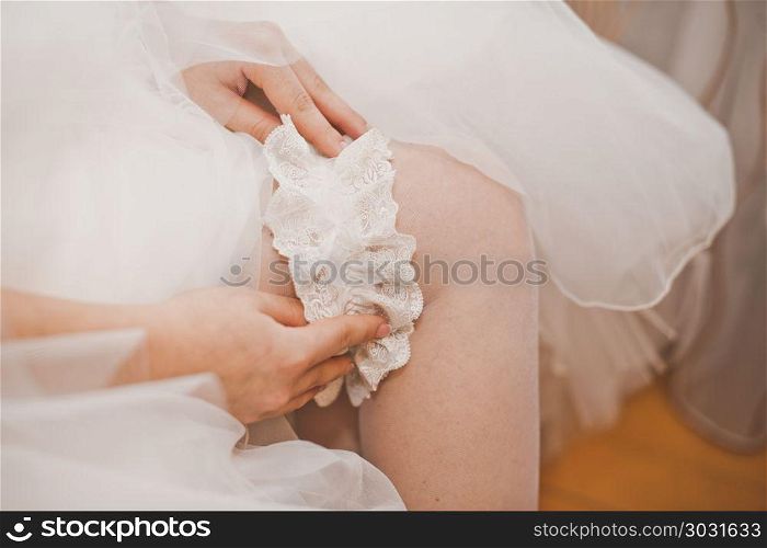 The young woman dresses an ornament on a foot before wedding.. The bride dresses an ornament on a foot.