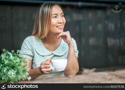 The young woman happily drinks coffee in the coffee shop.