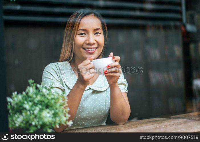 The young woman happily drinks coffee in the coffee shop.