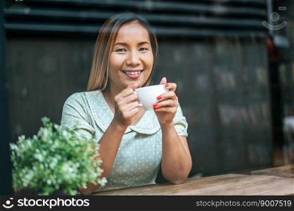 The young woman happily drinks coffee in the coffee shop.