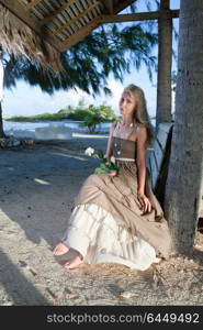 The young woman in a long sundress on a tropical beach. Polynesia. Island