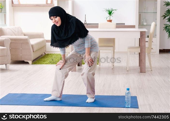The young woman in hijab doing exercises at home . Young woman in hijab doing exercises at home 