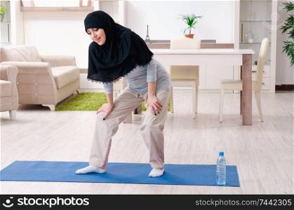 The young woman in hijab doing exercises at home . Young woman in hijab doing exercises at home 