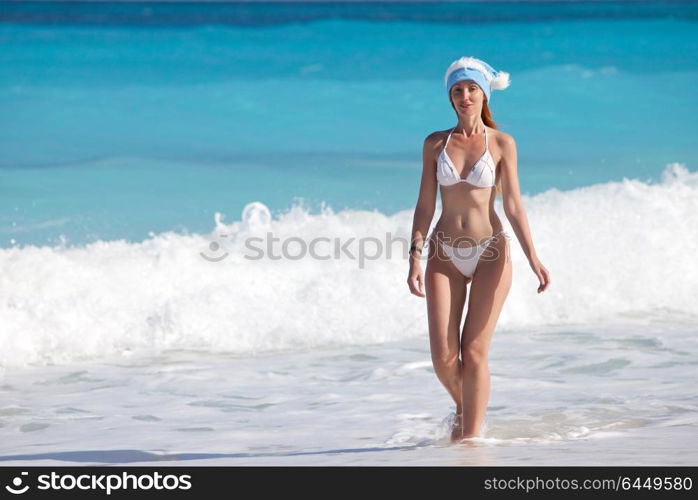 The young woman in the New Year&rsquo;s cap walks on a beach