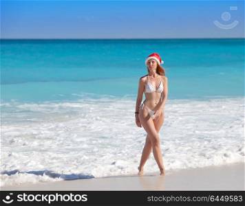 The young woman in the New Year&rsquo;s cap walks on a beach