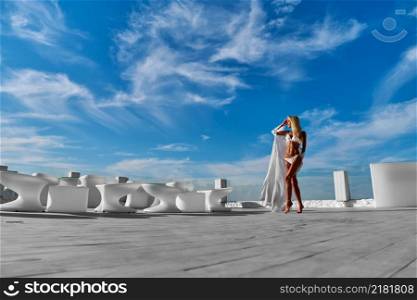 The young woman in white pareo on a terrace and blue sky on a background.. The young woman in white pareo on a terrace and blue sky on a background