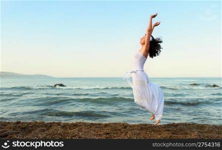 The young woman jumps on seacoast. A picturesque landscape