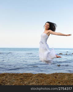 The young woman jumps on seacoast. A picturesque landscape