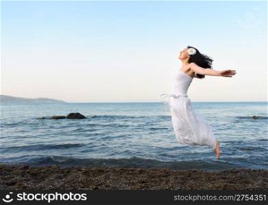 The young woman jumps on seacoast. A picturesque landscape