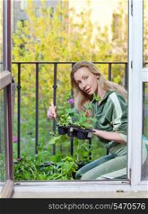The young woman lands seedling on a balcony