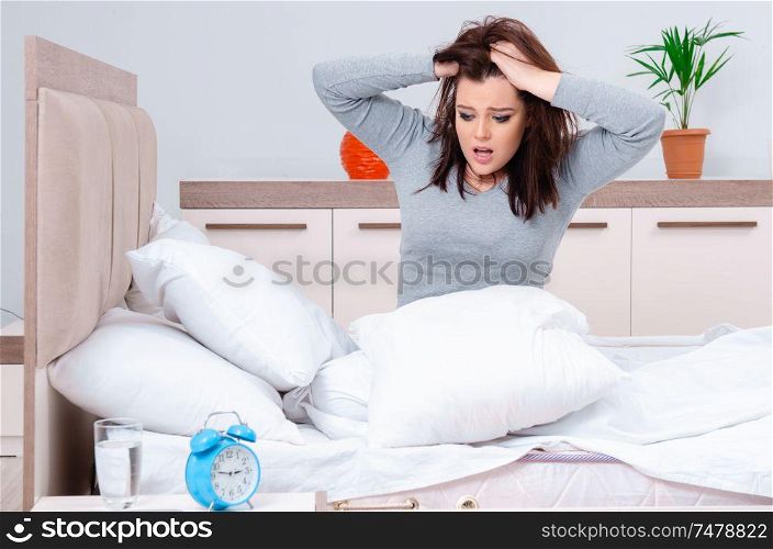 The young woman lying on the bed in time management concept . Young woman lying on the bed in time management concept