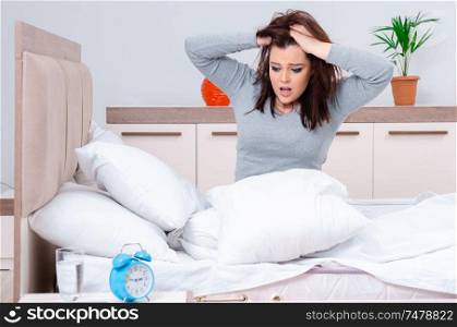 The young woman lying on the bed in time management concept . Young woman lying on the bed in time management concept