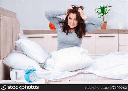 The young woman lying on the bed in time management concept. Young woman lying on the bed in time management concept