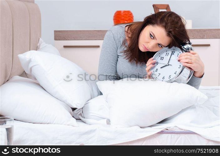 The young woman lying on the bed in time management concept. Young woman lying on the bed in time management concept