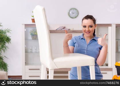 The young woman repairing chair at home . Young woman repairing chair at home 