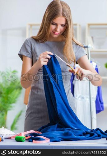 The young woman tailor working in workshop on new dress. Young woman tailor working in workshop on new dress