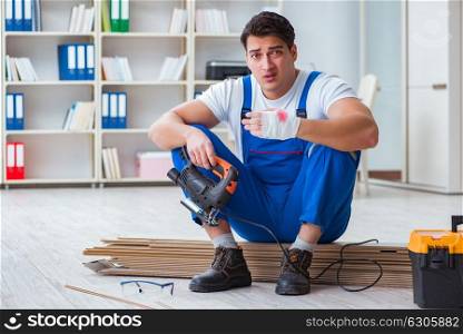 The young worker working on floor laminate tiles. Young worker working on floor laminate tiles