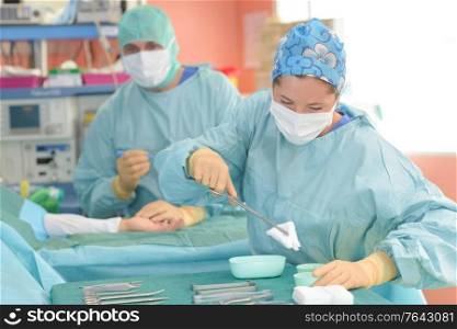 theater assistant preparing swab for surgeon