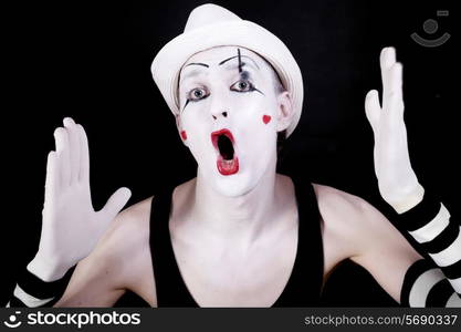 Theater funny mime with open mouth in white hat on black background