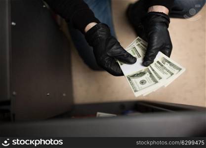 theft, burglary and people concept - thief stealing money from safe at crime scene. thief stealing money from safe at crime scene