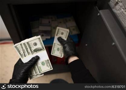 theft, burglary and people concept - thief stealing money from safe at crime scene. thief stealing money from safe at crime scene
