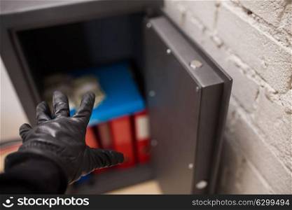 theft, burglary and people concept - thief stealing valuables from safe at crime scene. thief stealing valuables from safe at crime scene
