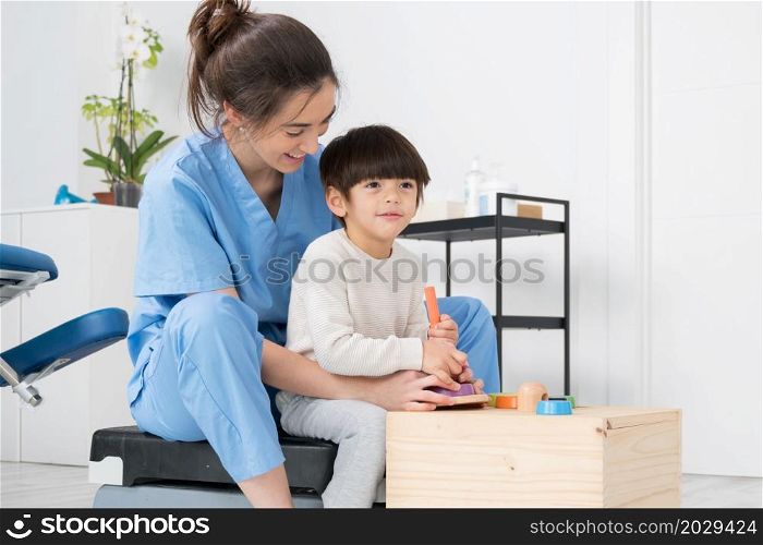 Therapist doing development activities with a little boy with cerebral palsy, having rehabilitation, learning . Training in medical care center. High quality photo.. Therapist doing development activities with a little boy with with cerebral palsy, having rehabilitation, learning . Training in medical care center