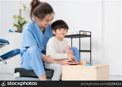 Therapist doing development activities with a little boy with cerebral palsy, having rehabilitation, learning . Training in medical care center. High quality photo.. Therapist doing development activities with a little boy with with cerebral palsy, having rehabilitation, learning . Training in medical care center