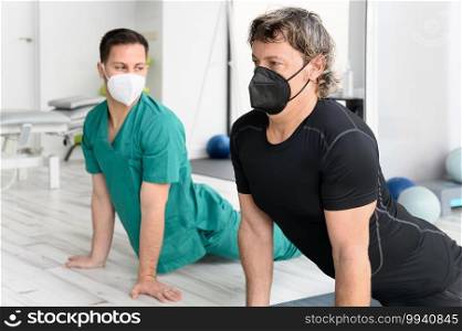 Therapist with protective face mask Assisting patient With Stretching Exercises. High quality photo. Therapist with protective face mask Assisting patient With Stretching Exercises.