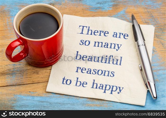 There are some many beautiful reasons to be happy - handwriting on a napkin with a cup of coffee
