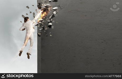 There is no barriers for her. Emotional businesswoman breaking stone wall with karate punch