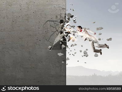 There is no barriers for her. Emotional businesswoman breaking stone wall with karate punch