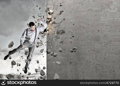 There is no barriers for him. Emotional businessman breaking stone wall with karate punch