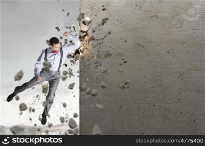 There is no barriers for him. Emotional businessman breaking stone wall with karate punch