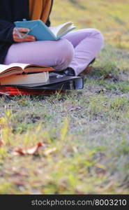 There is student reading book on the University campus area.