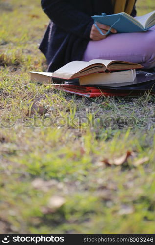 There is student reading book on the University campus area.