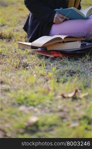There is student reading book on the University campus area.
