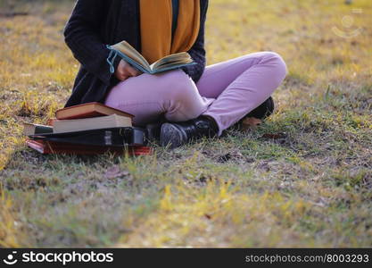 There is student reading book on the University campus area.